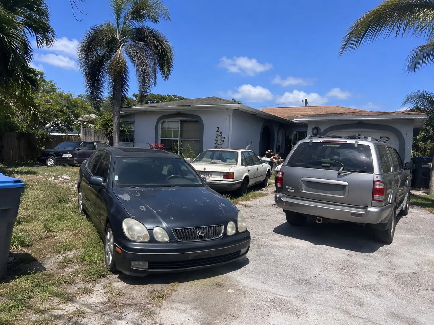 Junk cars including an old Lexus and an SUV parked in a Florida yard